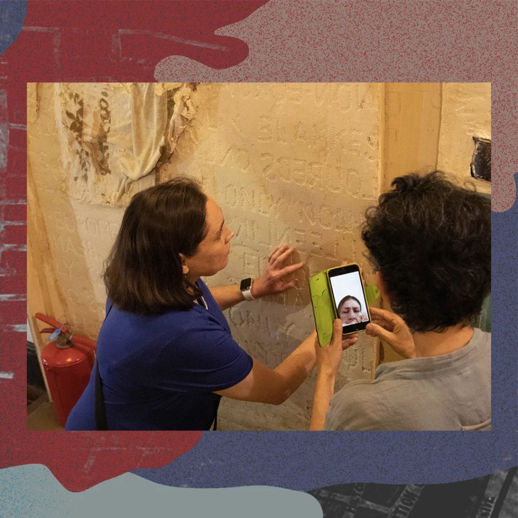 A blind white woman feels writing engraved in plasterwork.
