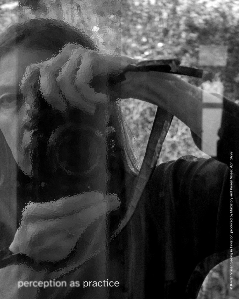 Black and white self-portrait of Karren Visser reflected in a window, holding a camera that hides part of her face, with a blurred strip over the camera and hands; an out-of-focus garden behind. Text reads “perception as practice.”
© Karren Visser. Seeing in Isolation, produced by Multistory and Karren Visser, April 2020.
