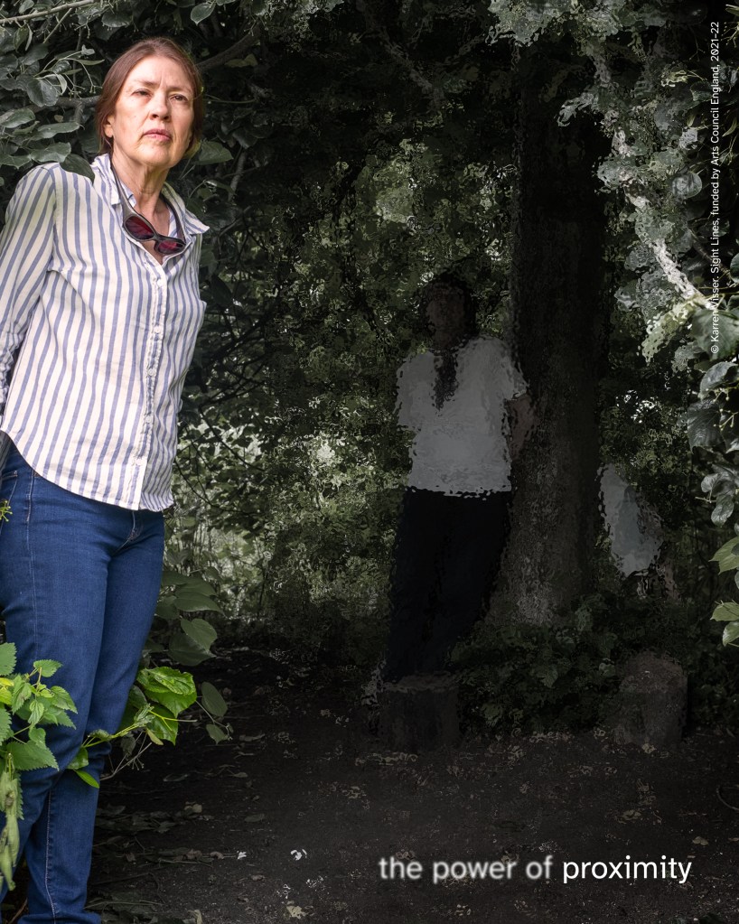 Woman standing beside tree with dense green foliage, serious expression, wearing striped shirt and jeans. Faint figure of woman in white T-shirt partly hidden under tree. Text reads “the power of proximity.”  © Karren Visser. Sight Lines, funded by Arts Council England, 2021–22.